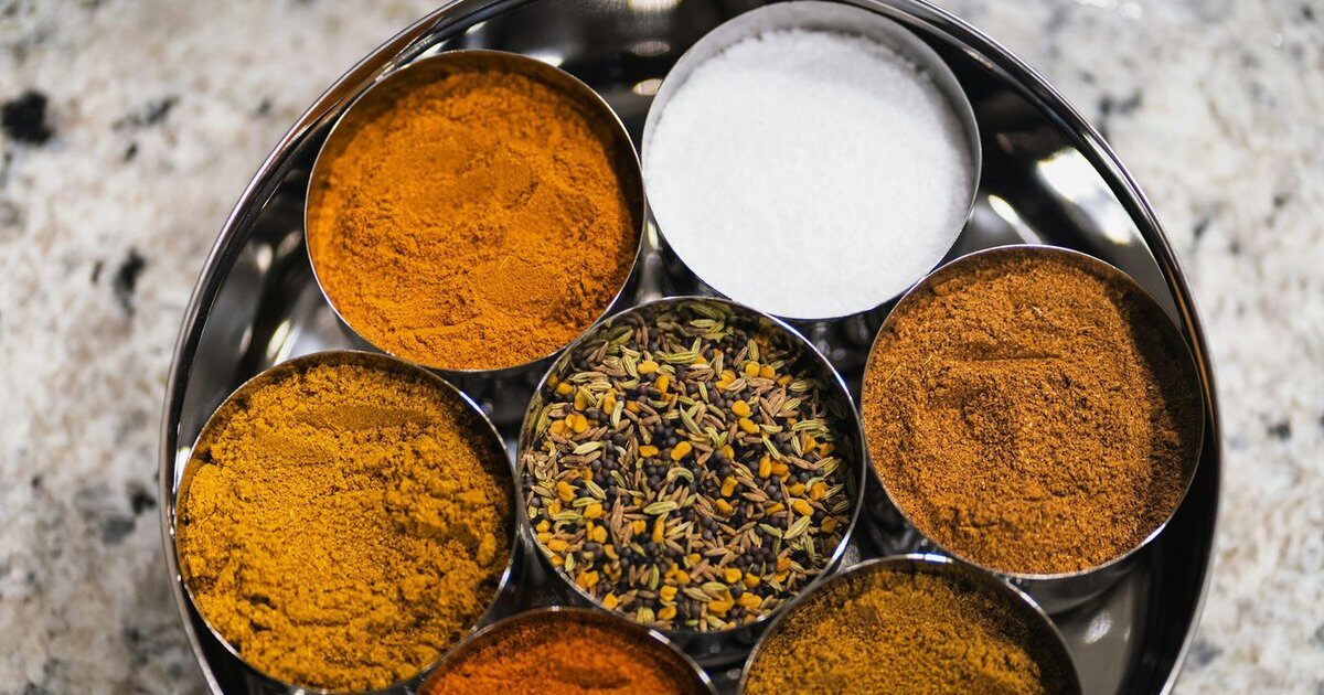 Colourful Indian spices and herbs spread on a dark surface